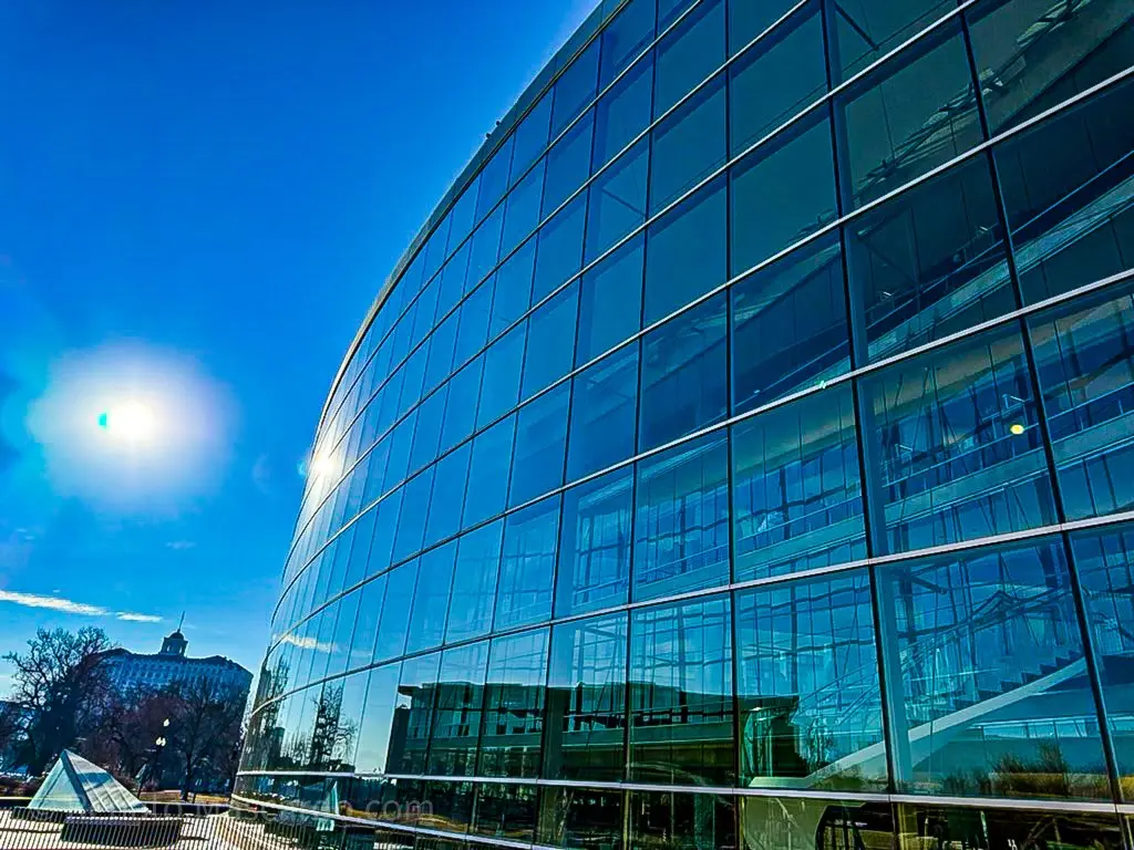 A modern glass building reflecting the blue sky and sunlight, showcasing its sleek architectural design.